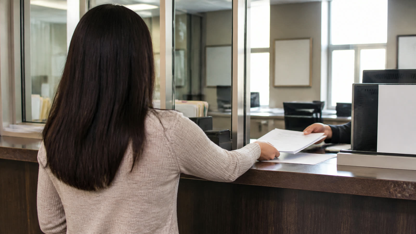 A person handing paperwork across a public service counter