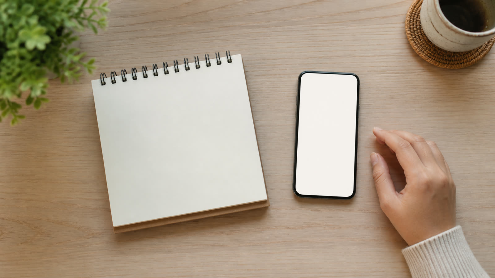 A blank notepad and a phone on a desk, seen from above