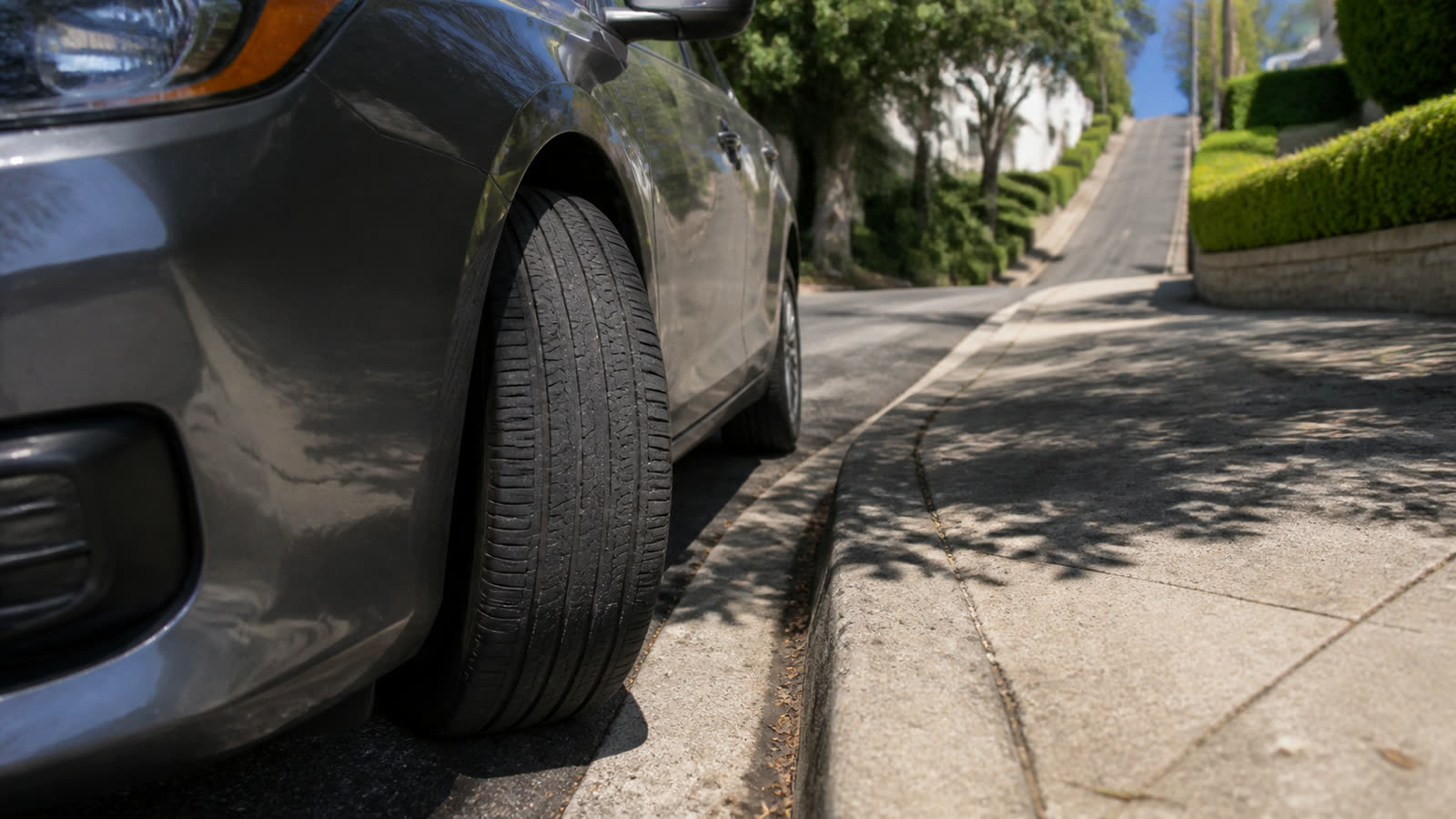 A car's front wheel turned in toward the curb on a steep residential hill
