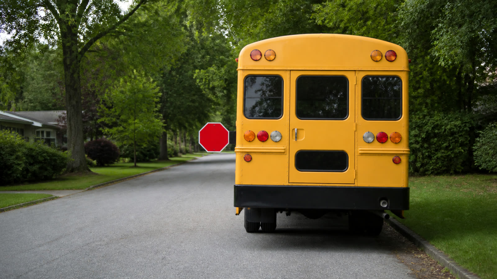A yellow school bus stopped on a residential street with its stop sign out